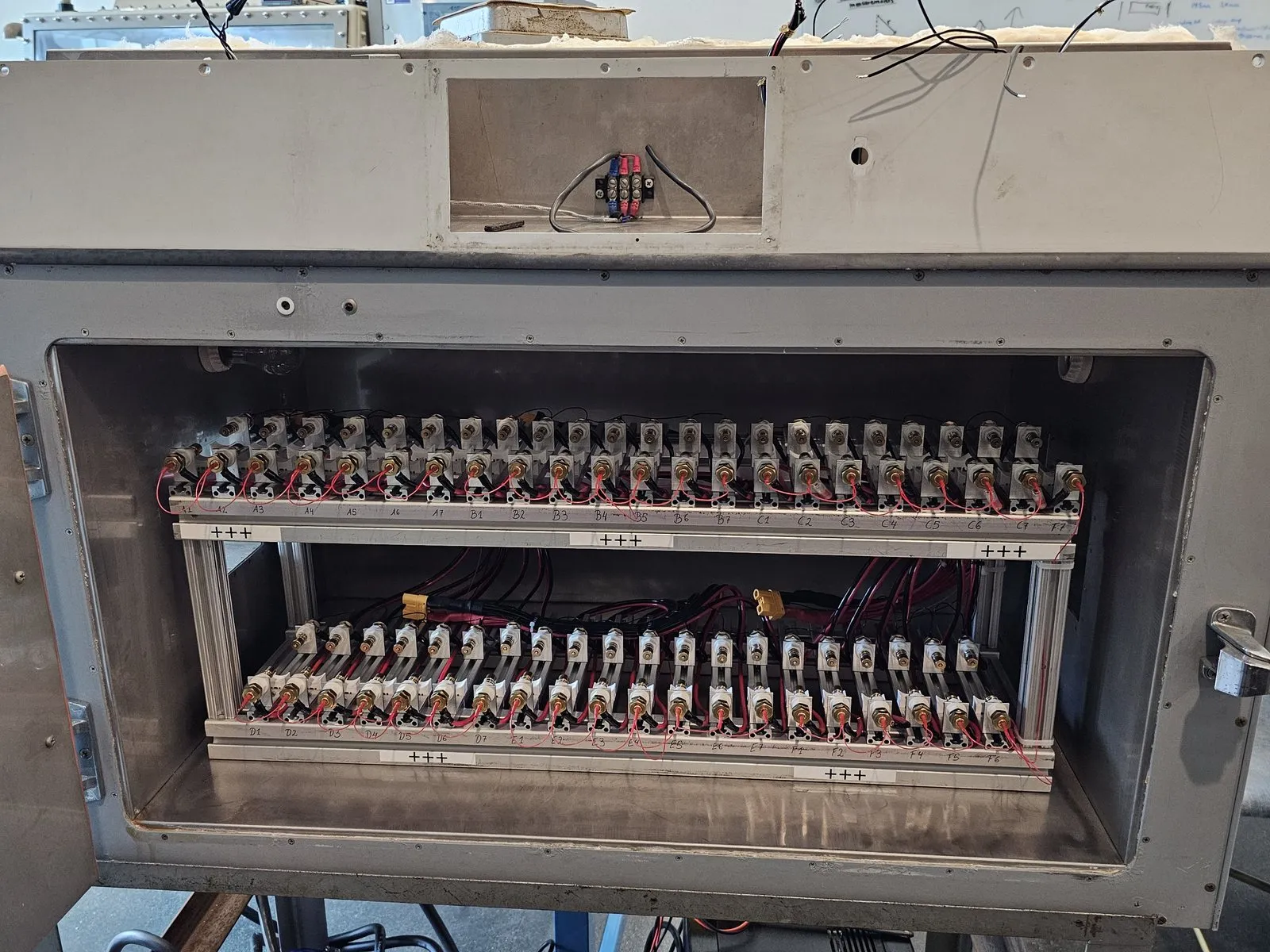 Open thermal chamber showing the two-row cell-holder array with balanced wiring harnesses
